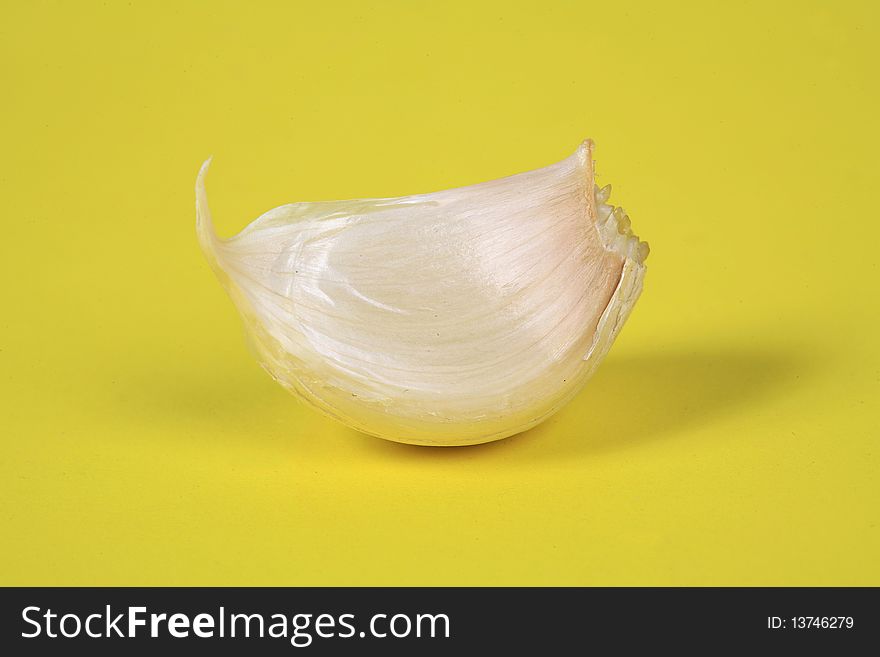 A slice of garlic on a yellow background image. A slice of garlic on a yellow background image