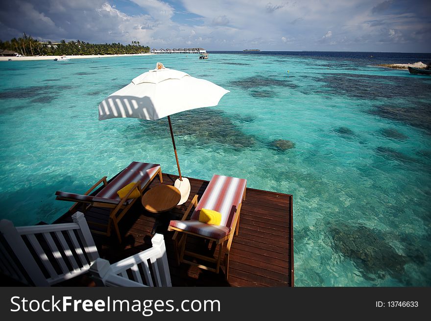 View of nice umbrella and teakwood chair in water villa. View of nice umbrella and teakwood chair in water villa.