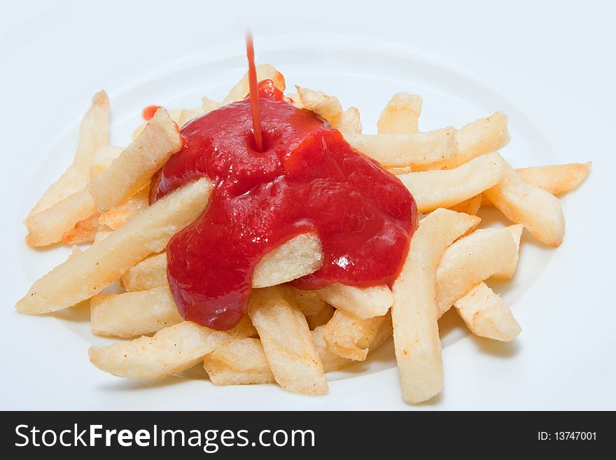 French fries being drenched in ketchup on white plate. French fries being drenched in ketchup on white plate