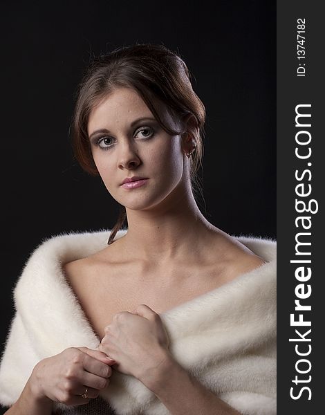 Portrait of beautiful young woman with fur coat against black background. Portrait of beautiful young woman with fur coat against black background.