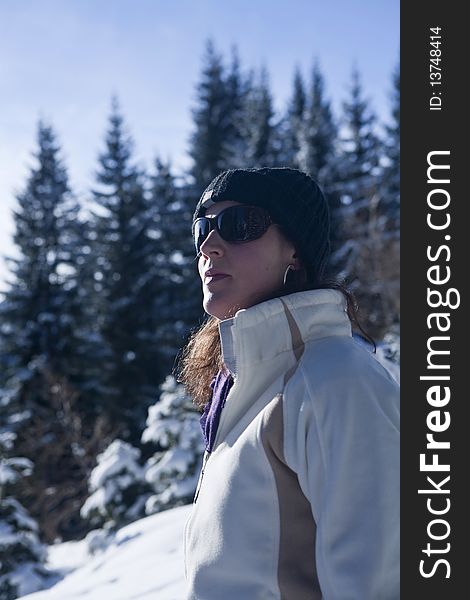 A young woman in a winter wonderland. Lot of snow and trees in the blury background.