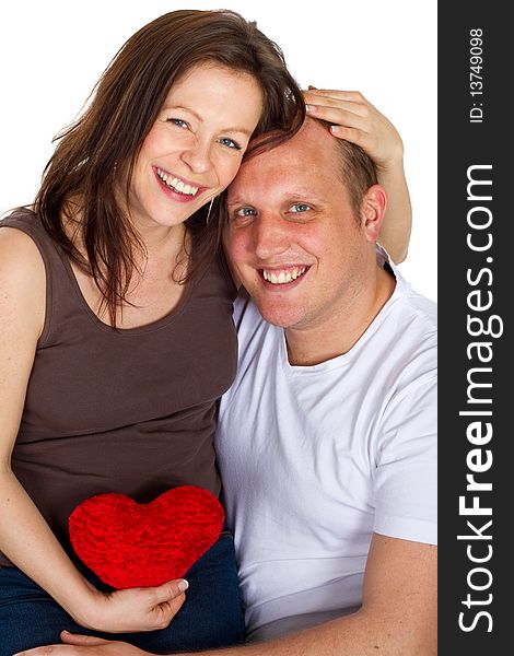 Young couple sitting in a chair holding a heart. Young couple sitting in a chair holding a heart.