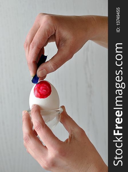 Female hands coloring an easter egg - painting a ladybug on it - behind gray. Female hands coloring an easter egg - painting a ladybug on it - behind gray