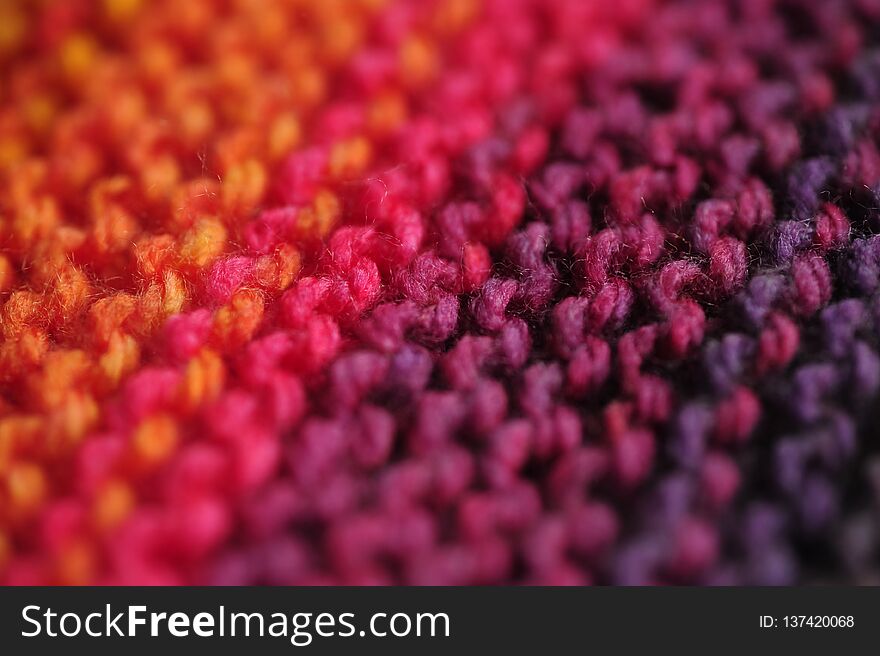 Close up of seamless knitted diagonal patterns in vivid rainbow mixed colors with shallow selective focus