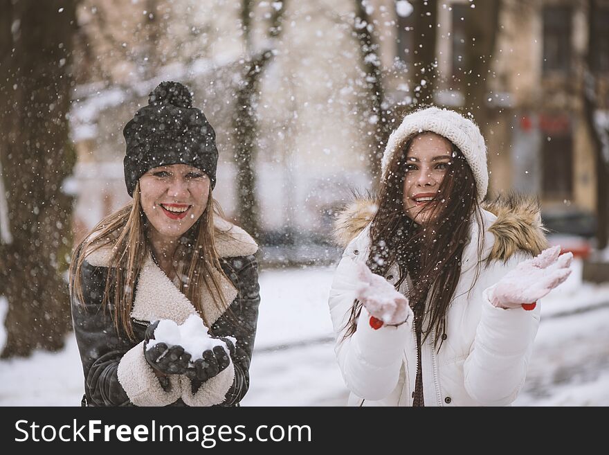 Two best female friends play with snow. Winter outdoor activities, positive emotions, joy and happiness