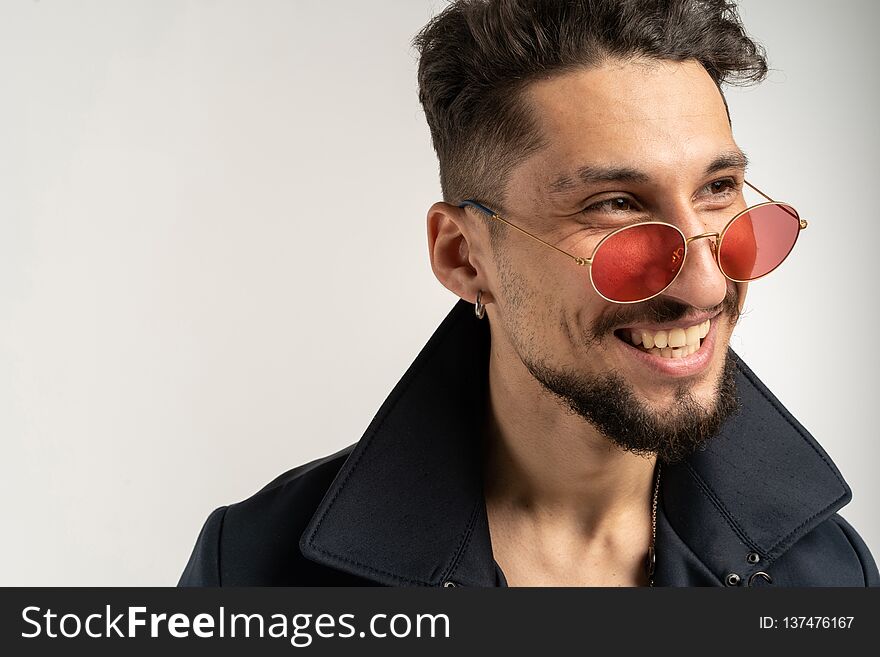 Close up portrait of smiling handsome man in sunglasses in black jacket