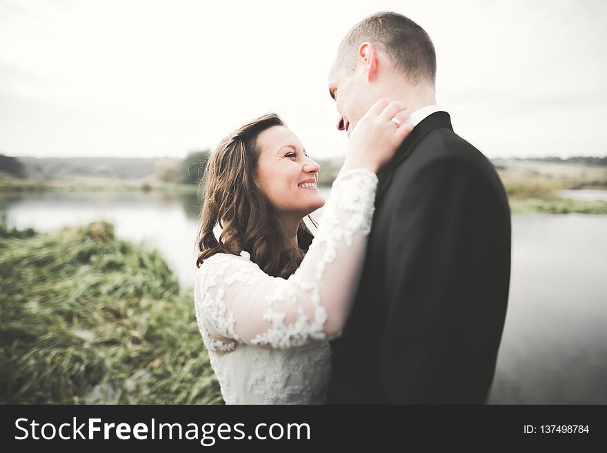 Romantic, fairytale, happy newlywed couple hugging and kissing in a park, trees in background