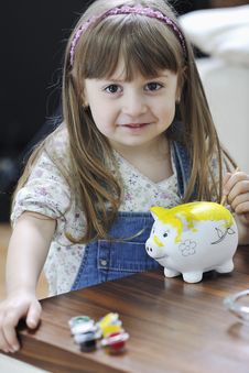 Cute Little Girl Painting Piggy Bank Stock Photo