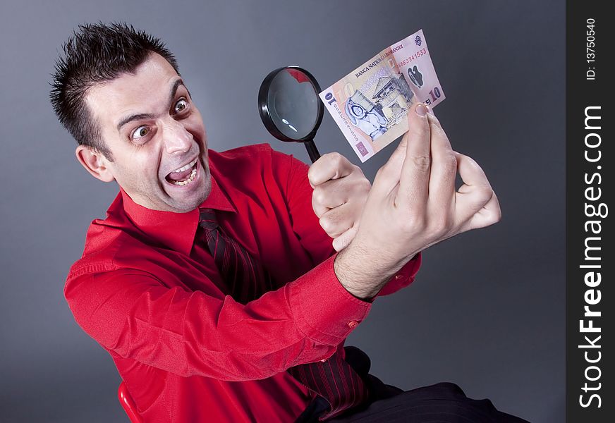 Funny businessman looking at banknote with magnifying glass