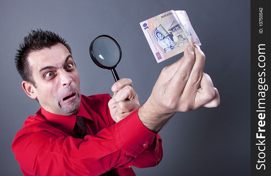 Funny businessman looking at banknote with magnifying glass