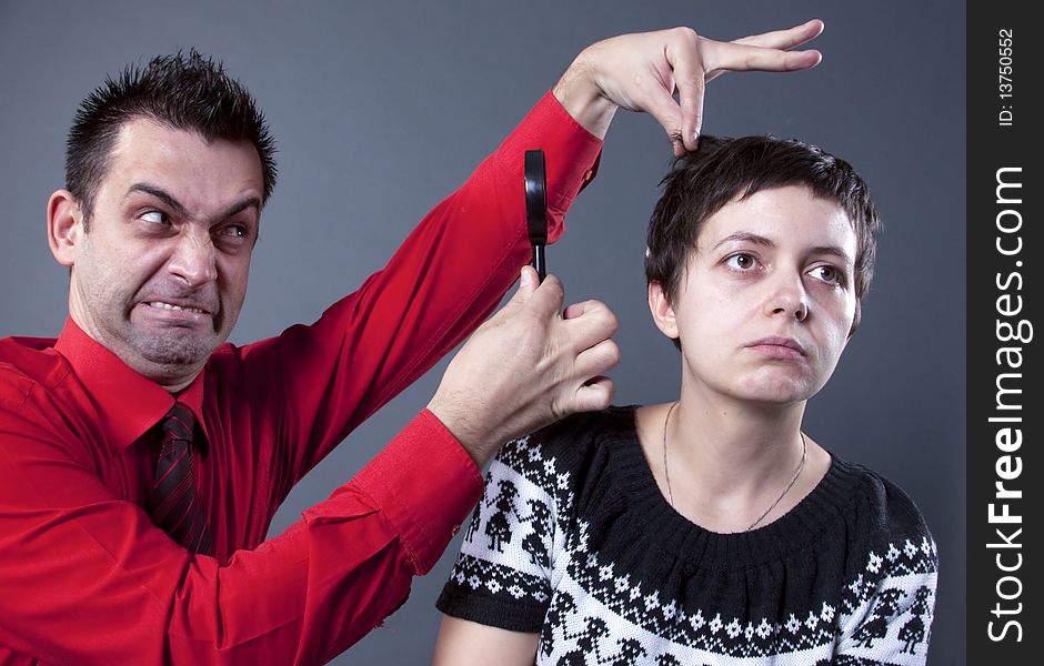 Man examining woman's hair with magnifying glass