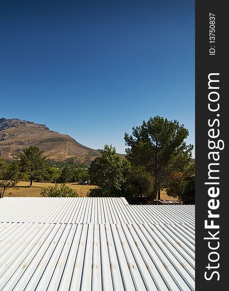 White sink roof of a modern hosue overlooking a mountain range with clear blue skies overhead. White sink roof of a modern hosue overlooking a mountain range with clear blue skies overhead