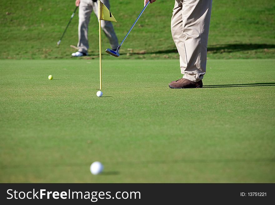 A golfer near the hole picking the ball