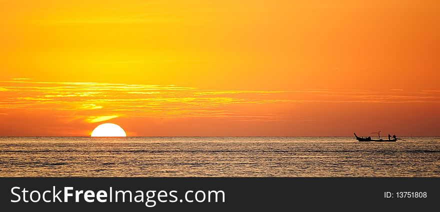 Sillhouette of a boat against the orange sunset