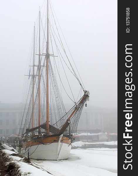 Old sailboat in foggy spring morning by pier