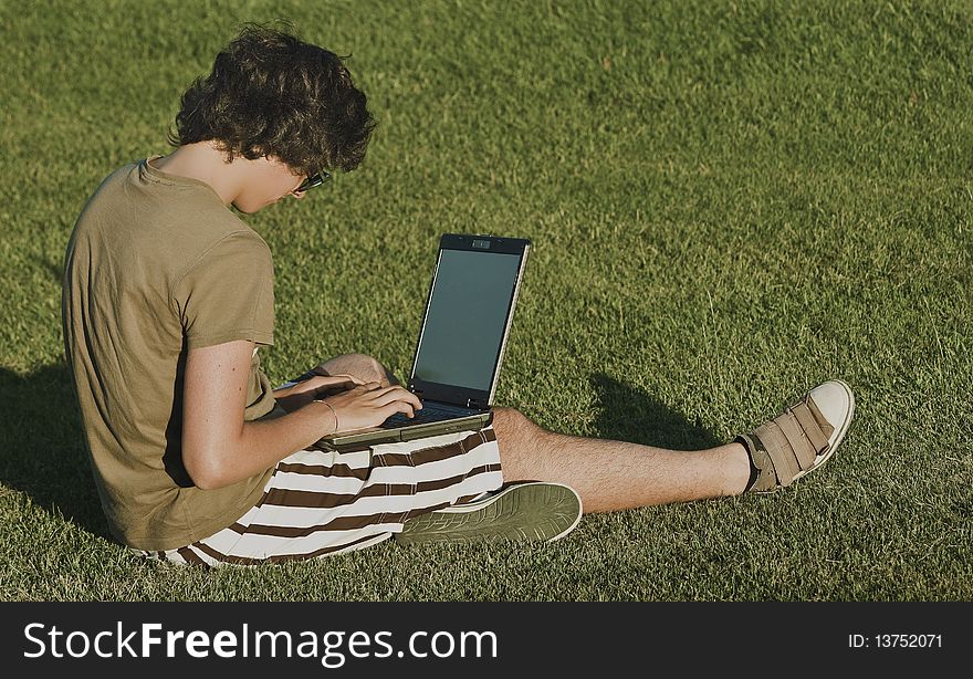 Young woman sitting in green grass, with desktop to the lap