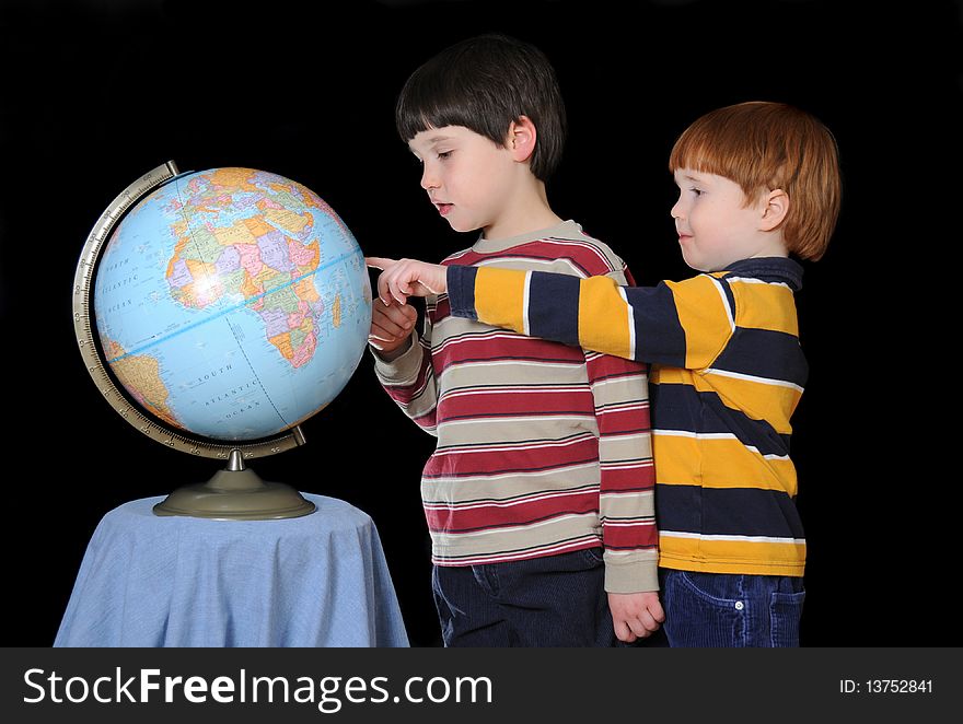 Two young boys identify various countries on the globe. Two young boys identify various countries on the globe