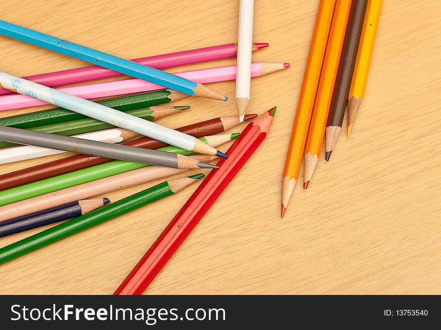 Colored Pencils Scattered on a Wood Background