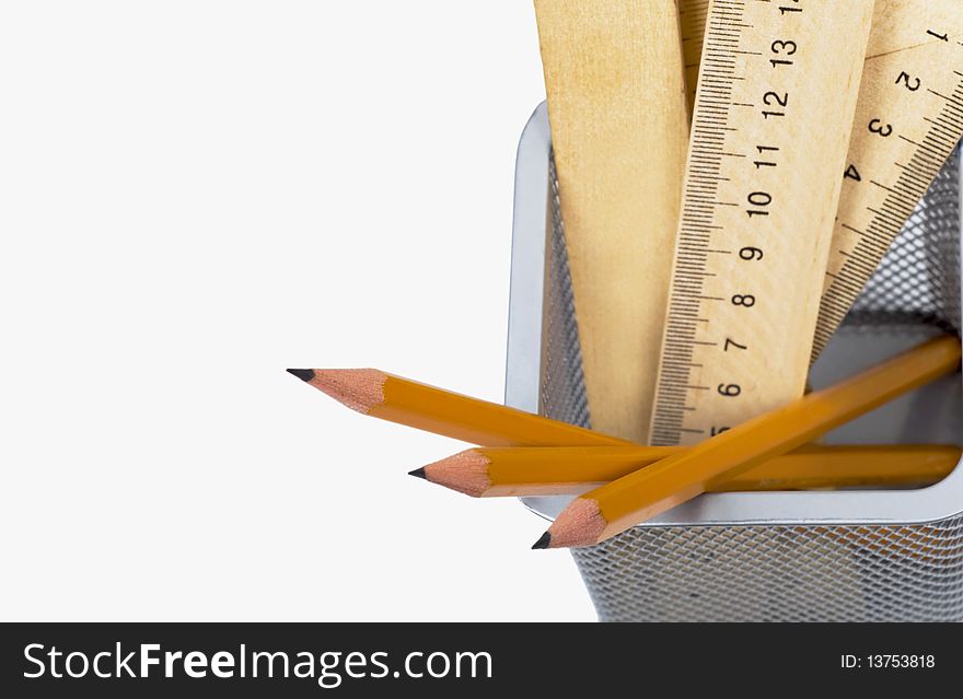 Simple pencils and wooden rulers in a support on a white background. Simple pencils and wooden rulers in a support on a white background