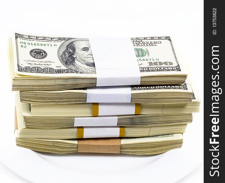 Pile of dollar denominations lies on white plate on white background. Pile of dollar denominations lies on white plate on white background