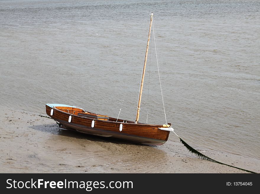 A lone sail boat beached on the shore. A lone sail boat beached on the shore