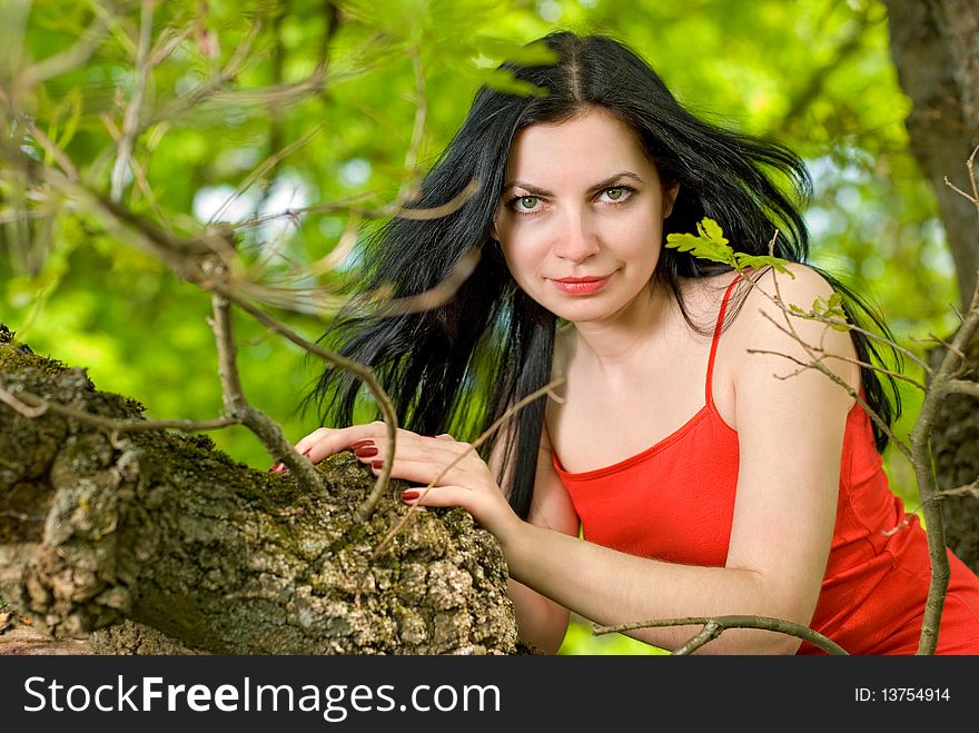 Young woman on tree in forest.