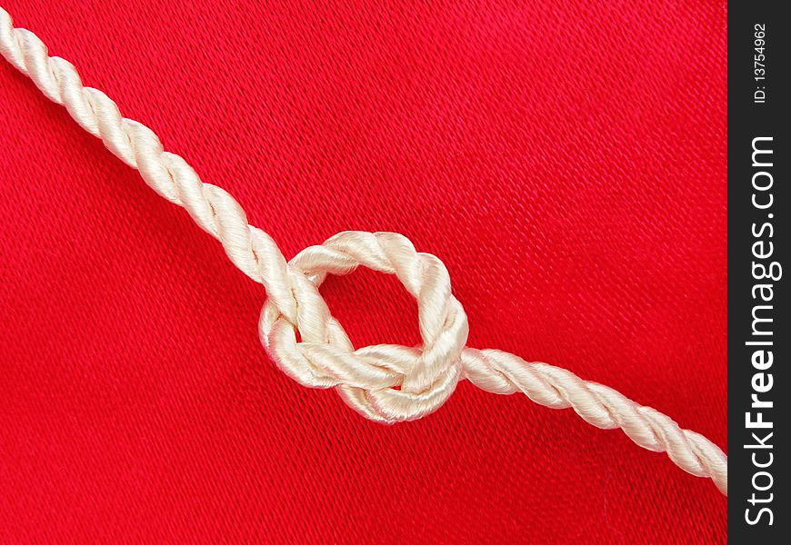 Close up of white rope knot on red background. Close up of white rope knot on red background