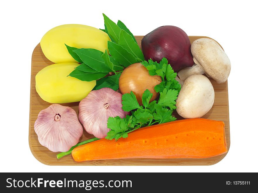 Board with potatoes, garlic, carrots, mushrooms, onions, bay leaf and parsley isolated on white