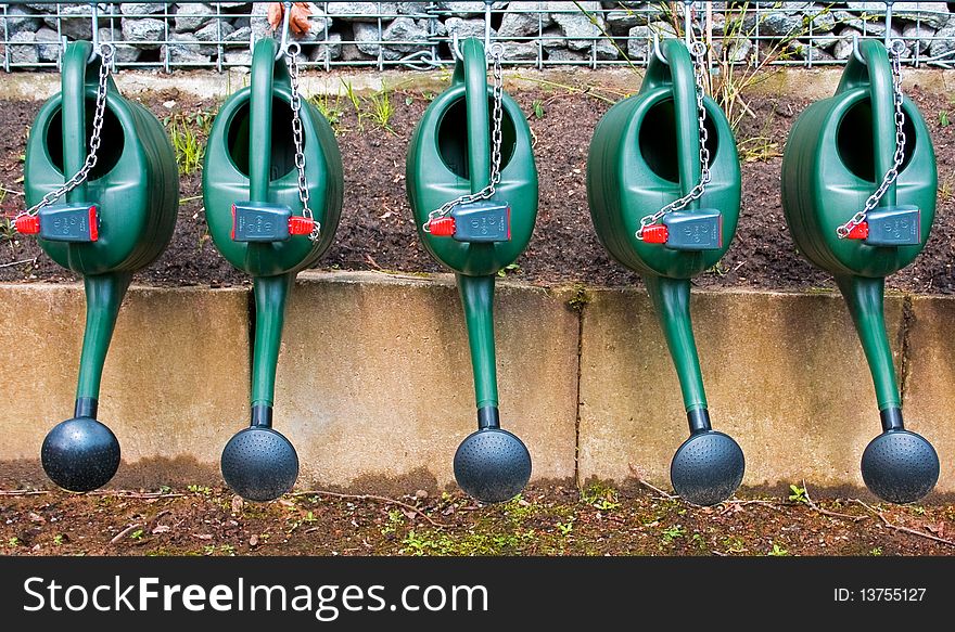 A number of watering cans in chains waiting for relief