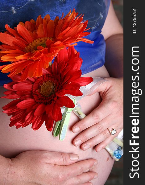 Image of a pregnant female holding flowers on her tummy. Image of a pregnant female holding flowers on her tummy