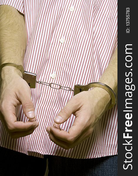 Caucasian man in a striped shirt on a green background hands handcuffed. Caucasian man in a striped shirt on a green background hands handcuffed