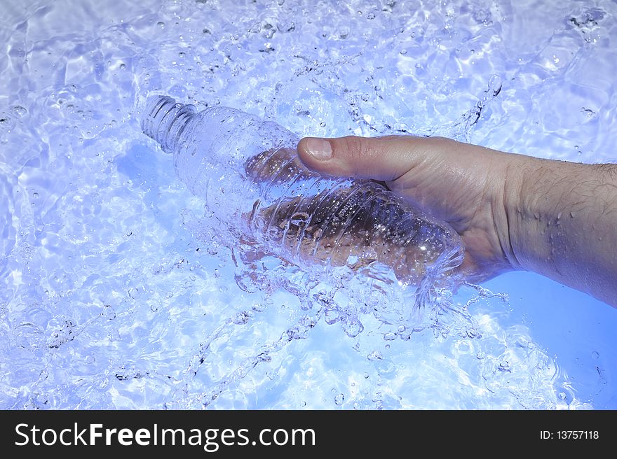 Hahd with plastic bottle in blue water