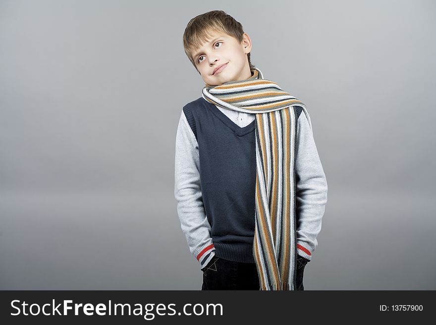 Caucasian teenager boy with natural pretty smile and dreaming facial expression weating colorful scarf and standing isolated over gray background with copyspace. Caucasian teenager boy with natural pretty smile and dreaming facial expression weating colorful scarf and standing isolated over gray background with copyspace