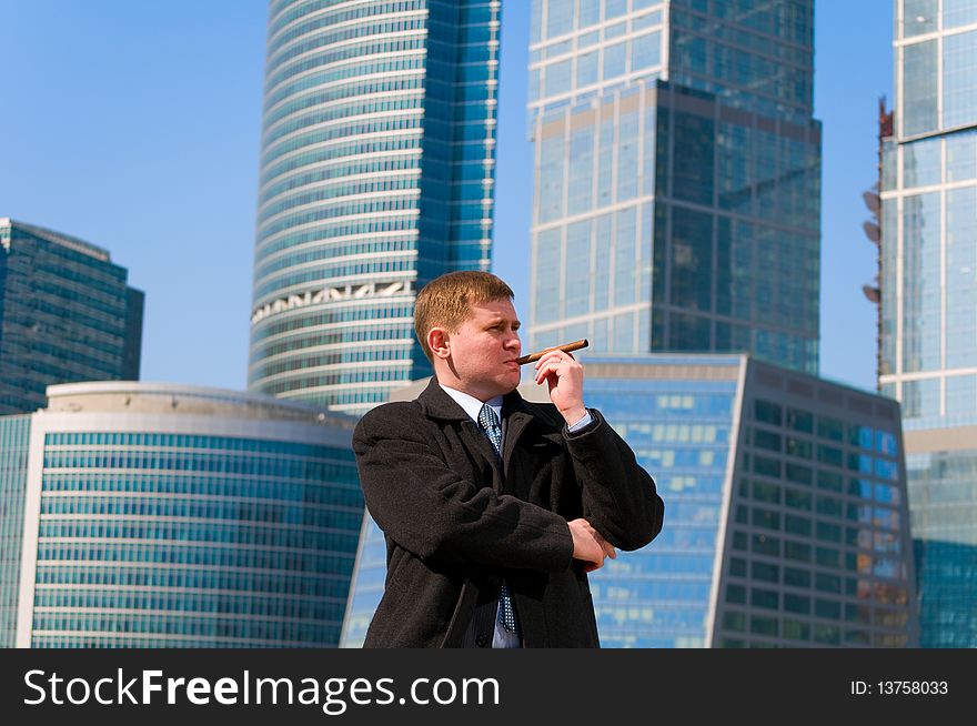 Businessman with cigar near skyscrapers