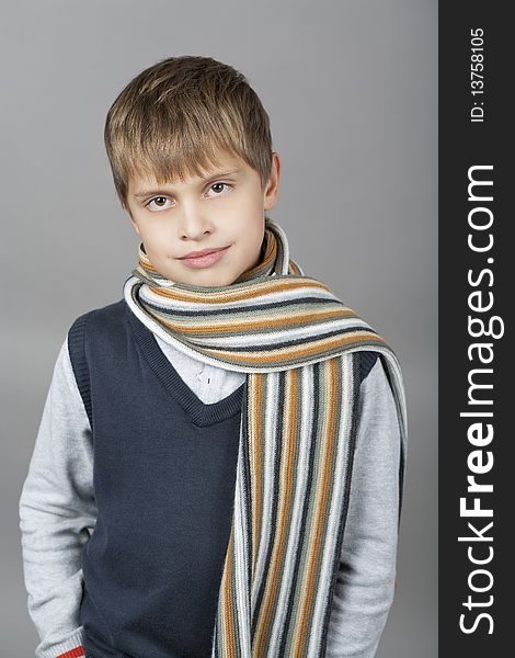 Cute and happy young caucasian teenager boy with elegant colorful scarf around and natural light smile standing isolated over gray background. Cute and happy young caucasian teenager boy with elegant colorful scarf around and natural light smile standing isolated over gray background