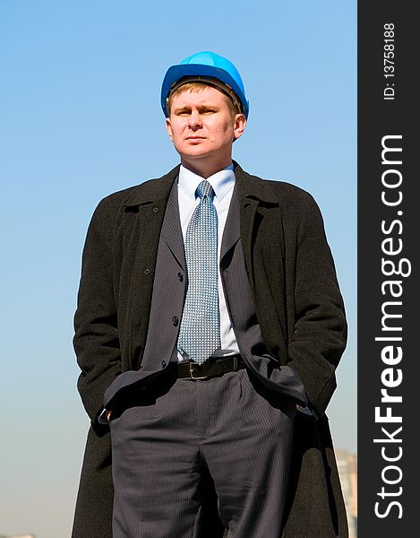 An engineer with blue hard hat standing confidently on sky background