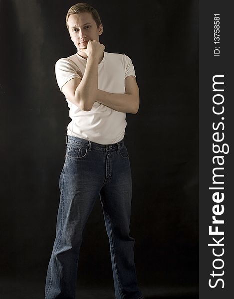 Young, European male model, wearing simple white t-shirt and jeans with black background. Young, European male model, wearing simple white t-shirt and jeans with black background.