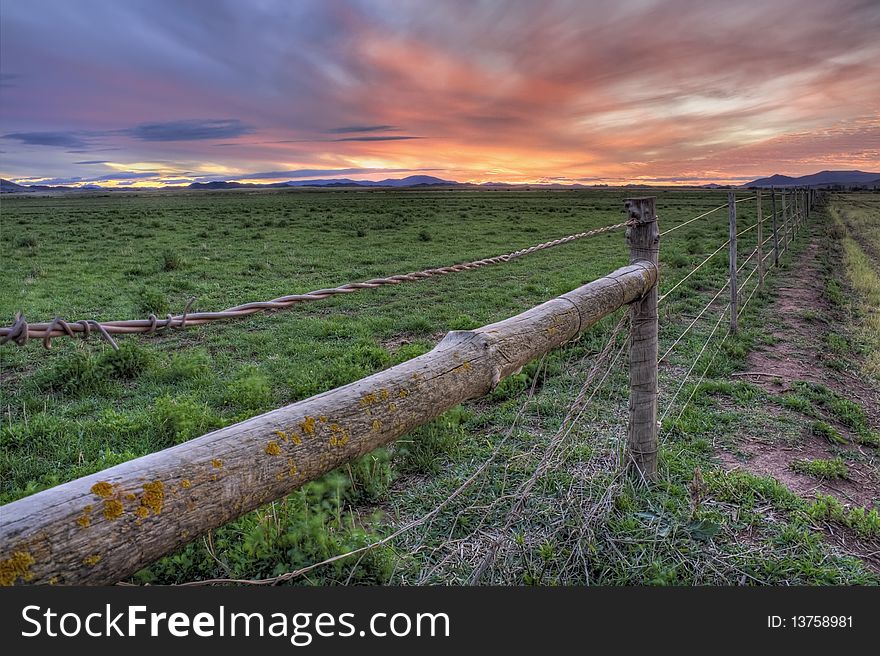A Fence cuts across a field at sunset. A Fence cuts across a field at sunset