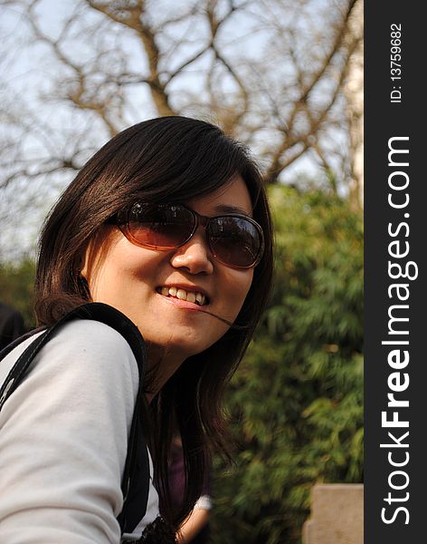 Chinese girl with sunglasses, green trees background