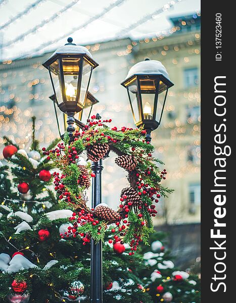 Street lamp decorated with christmas wreath pine cones, red berries, fir bunch. New year background