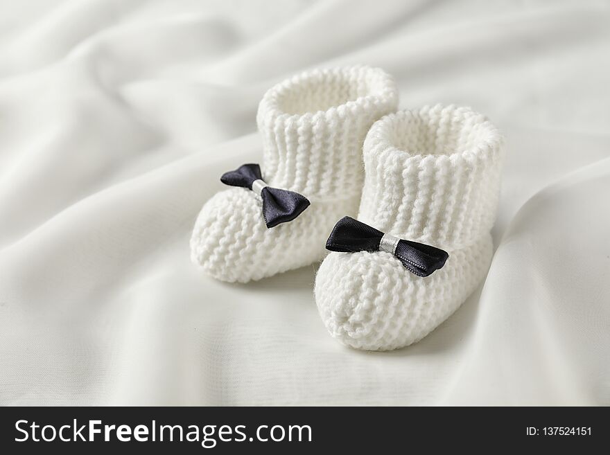 Handmade baby booties with bows on light plaid