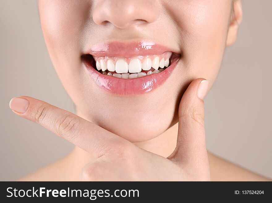 Beautiful young woman with healthy teeth on color background, closeup