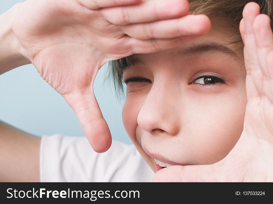 Cheerful boy shows frame with his hands