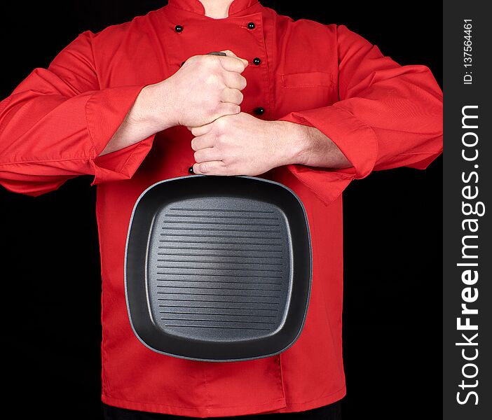 Cook in red uniform holding an empty square black frying pan