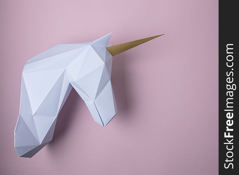 White 3d papercraft model of unicorn head on pink background. Minimal art concept.