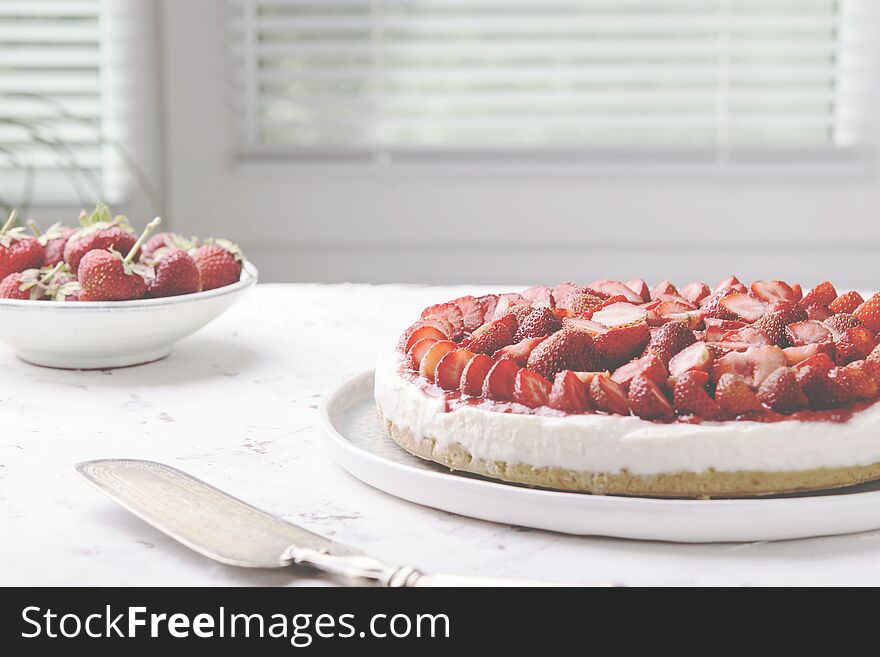Strawberry cheesecake on white table near window. Selective focus