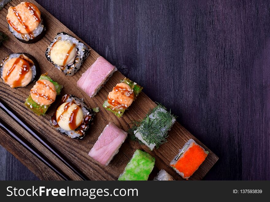 Assortment of baked and fresh sushi rolls on a wooden board