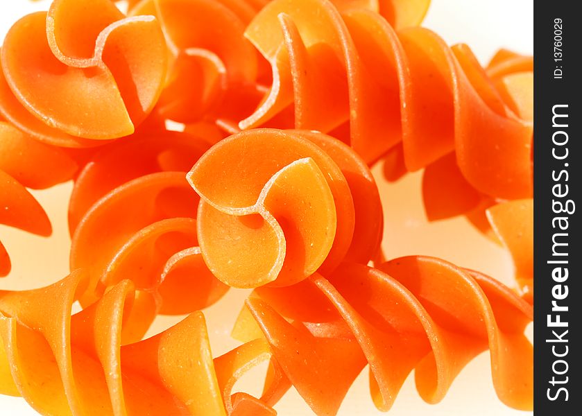 Orange pasta spirals against a white background.