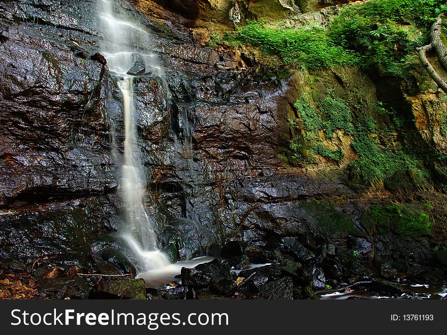 Beautiful multi-layered waterfall between vegetation.