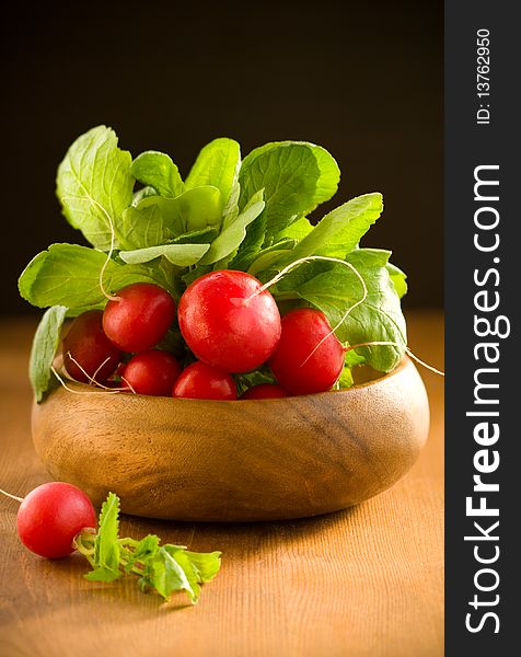 A bunch of fresh radishes in wooden bowl